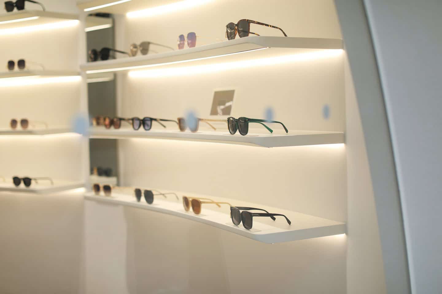 Stylish sunglasses displayed neatly on clean white retail shelves.