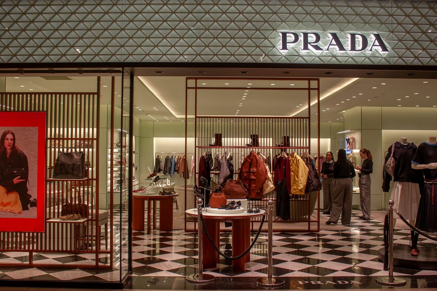 Staff members talk inside a luxury boutique with designer clothing.